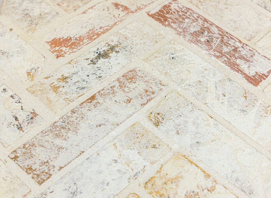 Whitewashed reclaimed brick laid in a herringbone pattern. Some of the natural brick color is visible through the whitewash.
