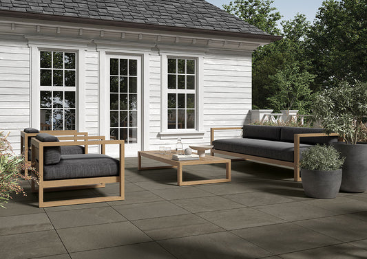 Patio area with modern / minimalist outdoor furniture. Ground is tiled with porcelain pavers that mimic bluestone.